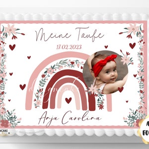 Pode incluir: Um topper de bolo rosa e branco com um design de arco-íris, detalhes florais e uma foto de uma menina pequena. O texto "Meine Taufe 17.02.2023 Anja Carolina" está impresso no topper.