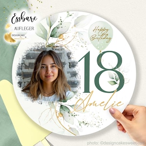 Könnte beinhalten: Runder essbarer Tortendekor mit grünem und weißem Blumendesign. Der Dekor verfügt über einen Fotorahmen, die Zahl 18 in Grün, den Namen "Amelie" in goldener Schrift und den Text "Happy Birthday".