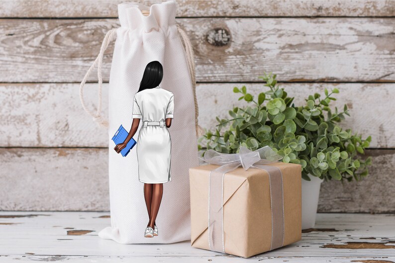 Puede incluir: Una bolsa blanca con cord&oacute;n con una ilustraci&oacute;n de una persona con un vestido blanco sosteniendo una carpeta azul. En la imagen tambi&eacute;n hay una caja de regalo envuelta con una cinta plateada y una peque&ntilde;a planta en maceta.