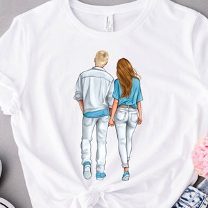 May include: White t-shirt with a graphic of a couple walking hand-in-hand. The man is wearing a white shirt and jeans, and the woman is wearing a blue shirt and jeans.
