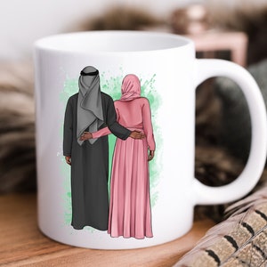 Puede incluir: Taza de cer&aacute;mica blanca con una ilustraci&oacute;n colorida de una pareja con ropa tradicional. El hombre lleva una t&uacute;nica negra y una cubierta de cabeza gris. La mujer lleva una t&uacute;nica rosa y un pa&ntilde;uelo en la cabeza. La pareja est&aacute; de pie uno junto al otro, con el brazo del hombre alrededor de la cintura de la mujer.