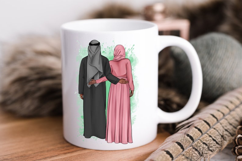 Puede incluir: Taza de cer&aacute;mica blanca con una ilustraci&oacute;n colorida de una pareja con ropa tradicional. El hombre lleva una t&uacute;nica negra y una cubierta de cabeza gris. La mujer lleva una t&uacute;nica rosa y un pa&ntilde;uelo en la cabeza. La pareja est&aacute; de pie uno junto al otro, con el brazo del hombre alrededor de la cintura de la mujer.