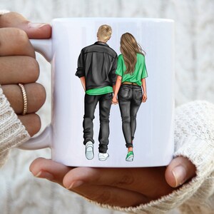 May include: White ceramic mug with a graphic of a couple walking hand-in-hand. The man is wearing a black jacket and jeans, and the woman is wearing a green shirt and jeans.