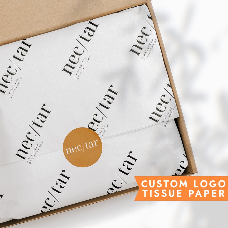 May include: A white tissue paper with a brown paper box. The tissue paper has a repeating pattern of the text "nec/tar A BALANCED WELLNESS SPA". A gold circle with the text "nec/tar" is visible on the tissue paper. The text "CUSTOM LOGO TISSUE PAPER" is visible in the lower right corner of the image.