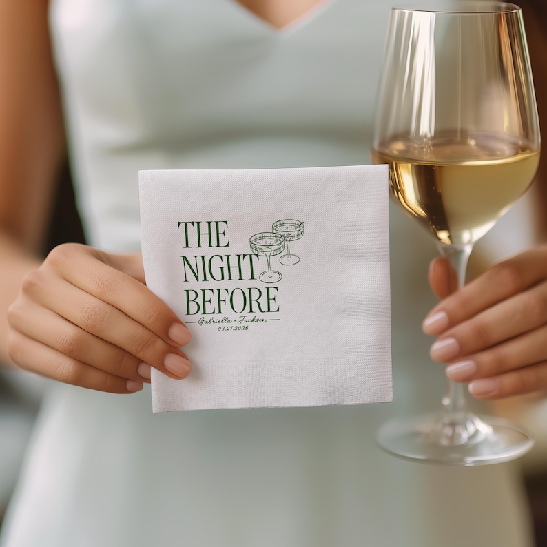 K&ouml;nnte beinhalten: Eine quadratische wei&szlig;e Papierserviette mit dunkelgr&uuml;nem Aufdruck THE NIGHT BEFORE, begleitet von einer Strichzeichnung zweier Cocktailgl&auml;ser sowie den Namen Gabriella und Jackson mit dem Datum 03.27.2026 darunter gedruckt.