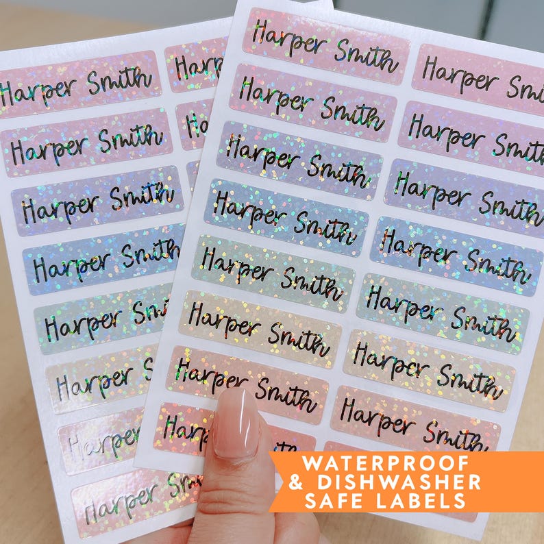 Op de afbeelding: Twee vellen rechthoekige etiketten met de naam "Harper Smith" in zwart script. De etiketten hebben een holografische, glitterende afwerking in pastelkleuren. De tekst "WATERPROOF & DISHWASHER SAFE LABELS" is in het oranje gedrukt.