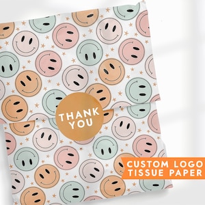 May include: White tissue paper with a repeating pattern of yellow smiley faces and stars. The paper has a sticker that says "Thank You" in the center.