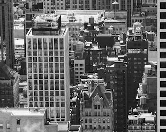Pode incluir: Fotografia aérea em preto e branco de um horizonte urbano com edifícios altos. A foto foi tirada de um ponto de vista elevado, mostrando os telhados dos edifícios e as ruas abaixo. A foto foi tirada em um dia claro e ensolarado.
