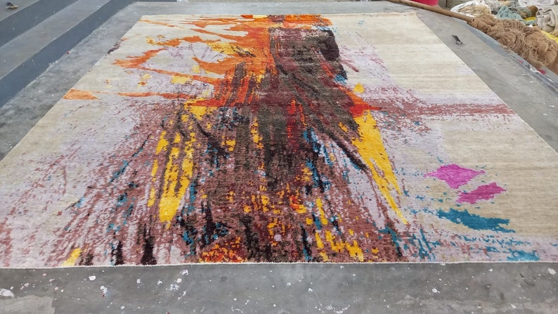May include: Abstract area rug with a colorful design featuring shades of yellow, orange, red, blue, and pink. The rug has a white background with a distressed look.