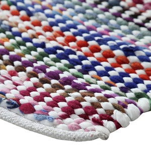 Puede incluir: Una alfombra tejida colorida con un borde blanco. La alfombra está hecha de hilo de diferentes colores y tiene un patrón de cuadros.