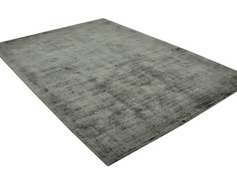 Op de afbeelding: Een rechthoekig, grijs vloerkleed met een getextureerd oppervlak. Het vloerkleed heeft een subtiel patroon en een donkere rand. Het vloerkleed wordt op een witte achtergrond weergegeven.