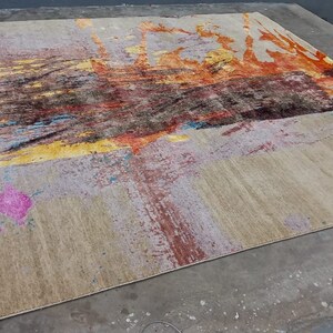 May include: Abstract area rug with a beige background and colorful abstract designs in shades of yellow, orange, pink, blue, and brown.