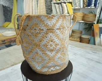 May include: A large, woven storage basket with silver accents and two handles. The basket is made of natural fibers and has a rustic, earthy look.