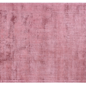 May include: A solid pink rug with a subtle textured pattern. The rug has a slightly distressed look, giving it a vintage feel.