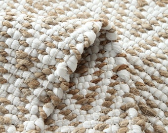 May include: Close-up of a woven rug with a white and brown pattern. The rug is made of natural fibers and has a textured surface.