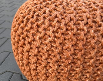 Op de afbeelding: Een ronde, geweven poef in een warme, aardse oranje tint. Het getextureerde oppervlak wordt gecreëerd door een dikke, geknoopte weefsel, waardoor het een ambachtelijke uitstraling heeft. Deze decoratieve poef kan worden gebruikt als voetensteun of extra zitplaats.