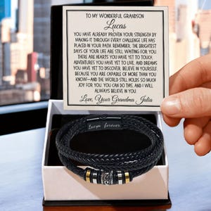 May include: A black leather wrap bracelet with metallic accents, presented in a gift box. The bracelet features the inscription "Love you forever." A card reads "To my wonderful grandson Lucas" with a heartfelt message from his grandma.