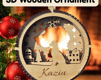 May include: A 3D wooden ornament with the text "3D Wooden Ornament". The ornament features a silhouette of a dog, houses, stars, and a snowflake design. The name "Kaziu" is written in cursive. Red Christmas ornaments are in the background.