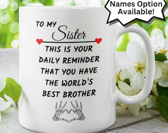 May include: White ceramic coffee mug with a black and white graphic of two hands making a heart shape. The mug has black text that reads "To My Sister This Is Your Daily Reminder That You Have The World's Best Brother".