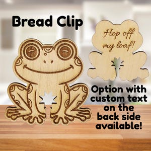 Puede incluir: Dos pinzas para pan con forma de rana de madera. Una pinza tiene el texto "Hop off my loaf!" y la otra tiene una cara de rana sonriente. La imagen también incluye el texto "Bread Clip" y "Option with custom text on the back side available!"