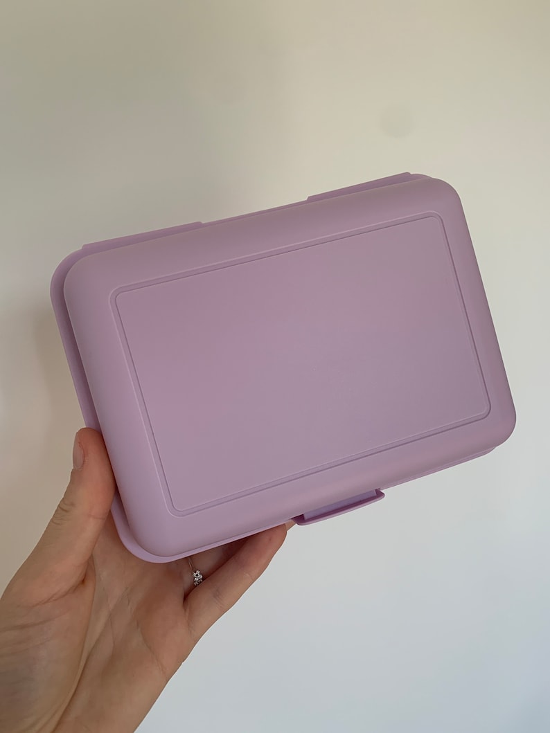 May include: A lavender plastic rectangular box with a latch on the front.