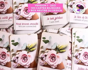 May include: A collection of 100 bilingual oracle cards featuring floral imagery of pink roses and eucalyptus leaves. Each card displays a message in both French and English, such as We are connected, I am lost, I have fears, and You are irreplaceable.