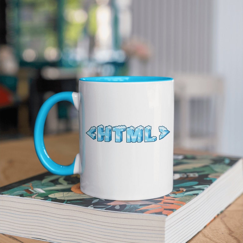 May include: White ceramic mug with a blue rim and handle. The mug features a graphic of the word "HTML" in blue with a frosted ice effect.