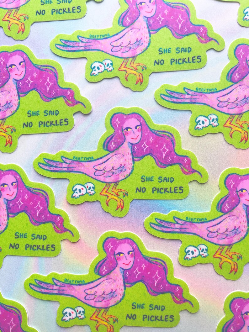 May include: A selection of stickers with a quirky design of a bird-woman with pink hair and a smiling face. The stickers have a green background and the text "SHE SAID NO PICKLES".