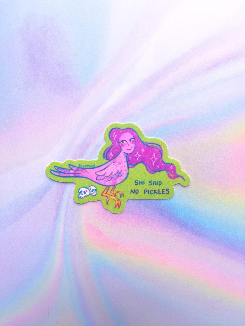 May include: A sticker depicting a fantastical bird-like figure with pink hair and a smiling face. The creature is pink and purple with yellow legs, set against a green backdrop. The text "SHE SAID NO PICKLES" is visible.