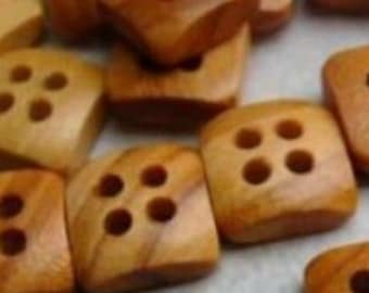 May include: A collection of square wooden buttons with four holes each. The buttons are a warm, light brown color with visible wood grain. They are scattered on a light-colored surface, suggesting a craft or sewing project.