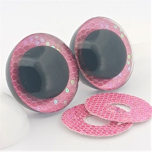 May include: Two large, black-pupiled, round craft eyes with a pink, textured border and iridescent glitter accents. Two matching pink, textured washers are also included. These are ideal for creating handmade dolls and toys.