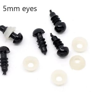 May include: Black plastic safety eyes with washers for crafts. The text "5mm eyes" is in the upper left corner. The eyes are black with a rounded head and a threaded post. White washers are also included.