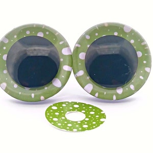 May include: Two large, green, googly eye-shaped craft pieces with white polka dots and a matching smaller piece. The eyes have a dark centre and a light green border. The pieces are likely for crafting or art projects.