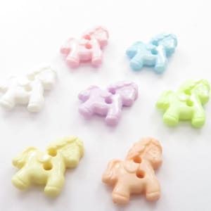 Op de afbeelding: Een verzameling kleurrijke paardvormige knopen in verschillende pastelkleuren, waaronder roze, blauw, groen, geel en oranje. Elke knoop heeft twee gaten om op te naaien en is gemaakt van glanzend plastic. Deze knopen zijn ideaal voor knutselprojecten.
