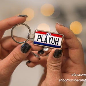 May include: A silver keychain with a blue, red, and white Ohio license plate design that says "PLAYUH".