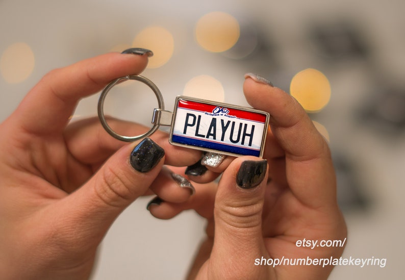 May include: A silver keychain with a blue, red, and white Ohio license plate design that says "PLAYUH".