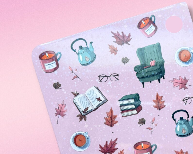 May include: A pink sticker sheet with fall-themed illustrations. The sheet features images of a teal teapot, a green armchair, burning candles in mugs, open books, fall leaves, and eyeglasses. The illustrations are in a watercolor style.