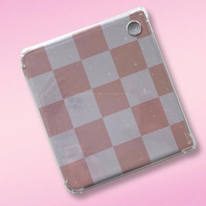 May include: A clear phone case with a pink and white checkered pattern. The case has a small hole for the camera lens.