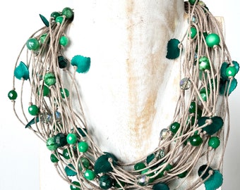 Collana “Errore” multifilo, in canapa avana, annodata con cristalli, pietre e micro foglie in resina verde.