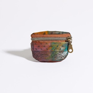 May include: A small, round coin purse with a zipper closure. The purse features a colorful, patterned design with shades of orange, green, and purple. The bottom edge has a decorative, embossed metal band. The zipper pull is a gold color.