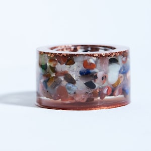 Pode incluir: Um anel transparente com uma banda de cobre e uma variedade de pedras coloridas incrustadas dentro.