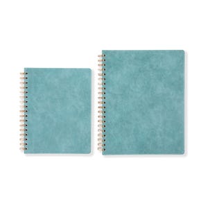 May include: Two teal-colored spiral notebooks of different sizes are displayed against a white background. The notebooks have a textured cover and gold-colored spiral binding. The larger notebook is positioned to the right of the smaller one.