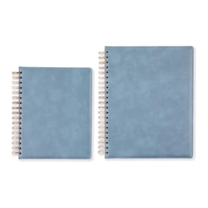 May include: Two blue spiral-bound notebooks of different sizes. The covers have a textured appearance. The spiral binding is gold-colored. The notebooks are set against a white background.