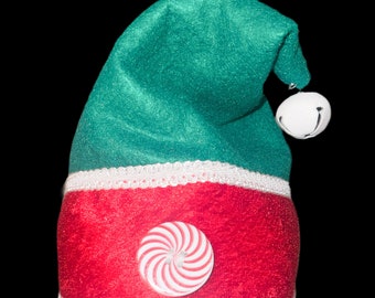 May include: A green and red elf hat with a white bell and a candy cane design.