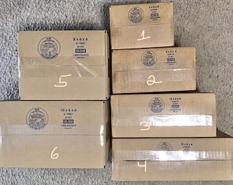 May include: An assortment of six cardboard boxes of different sizes, stacked together. The boxes are marked with numbers and product details, including dimensions like 20 x 15 x 15 cm and 25 x 15 x 15 cm. The boxes are sealed with clear tape.