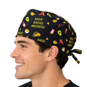 Puede incluir: Un gorro quirúrgico negro con un patrón repetitivo de tacos, aguacates, chiles y botellas de salsa picante. El texto "NACHO AVERAGE ANESTHESIA" está impreso en letras amarillas sobre la tela. El gorro incluye cintas para atar en la parte posterior.
