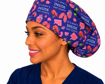 May include: A blue scrub cap featuring a repeating pattern of various human organs including hearts, lungs, and livers, interspersed with the white text "IT'S WHAT'S INSIDE THAT COUNTS". The cap has a gathered back with a black adjustable toggle.