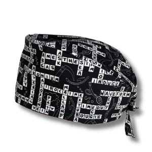 Puede incluir: Un gorro de quirófano negro y blanco con un diseño de crucigrama con términos médicos. El gorro tiene un lazo en la parte posterior.