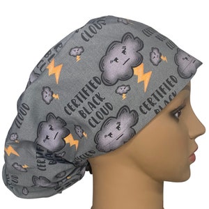 May include: Gray scrub hat with a repeating pattern of black clouds with angry faces and yellow lightning bolts. The text "Certified Black Cloud" is repeated throughout the pattern.