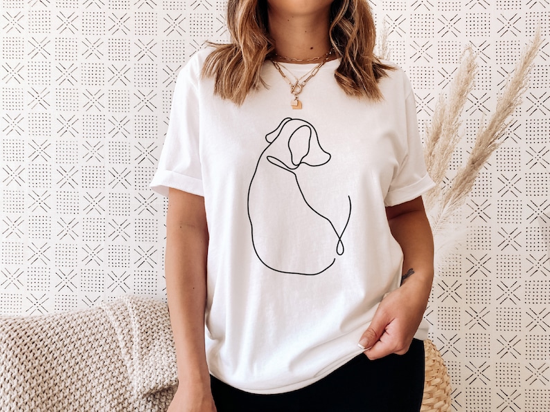 May include: White t-shirt with a black line drawing of a dog on the front.
